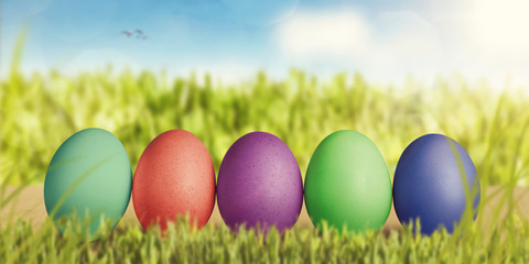 Reihe bunter Eier in grüner Landschaft