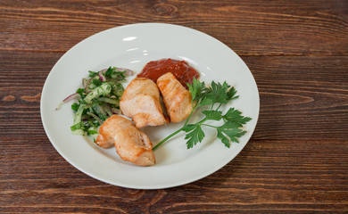 Roasted chicken breast fillet on a plate. Appetizing dish on the wooden brown table.