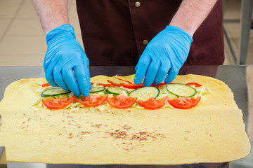 Cooking shawarma. Chef puts the ingredients on the pita bread.