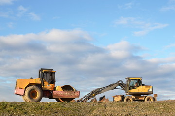 Two construction vehicles on uncultivated terrain
