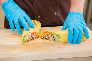 Cook shows the filling shawarma on wooden board.