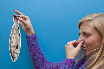 young woman keeping a paper fish with revolting expression - the concept of English proverb 