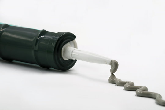 Silikonpistole mit ausgepressten grauen Silikon isoliert auf wei&szlig;