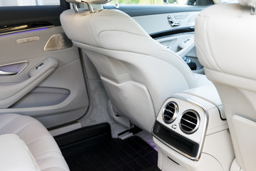 White leather interior of the luxury modern car. Leather comfortable white seats and multimedia. exclusive wood and metal decoration. Modern car interior details.