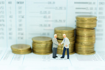 Miniature people : Businessman standing on bank book, join hands to do business together. Image use...