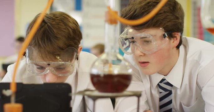 4k, Two school boys with digital tablet examining liquid in beaker. Slow motion.