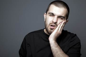 Young man at toothache isolated on gray