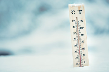Wooden thermometer in the snow. Four degrees Celsius on the plus after snowfall.