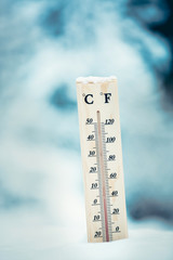 Wooden thermometer in the snow. Four degrees Celsius on the plus after snowfall.