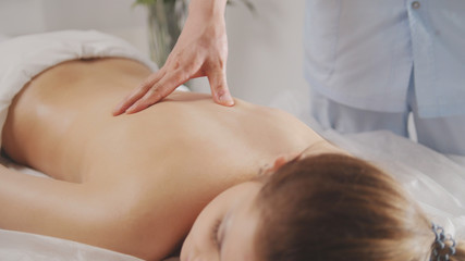 Fototapeta na wymiar Blonde young woman model receiving relaxing massage in spa room