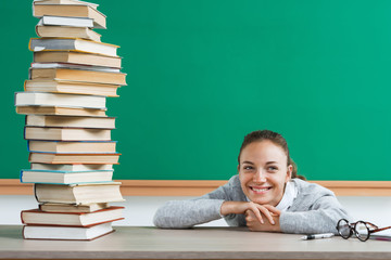 Happy young student with pile of books. Photo of teen schoolgirl in classroom, creative concept with Back to school theme