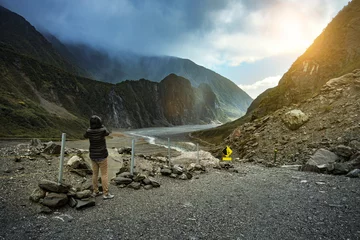 Poster tourist taking a photograph at fox glacier trekking trail most popular traveling destination in west coast southland new zealand © stockphoto mania