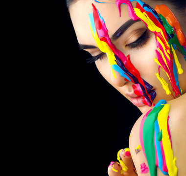 Beauty model girl with colorful paint on her face. Portrait of beautiful woman with flowing liquid paint isolated on black