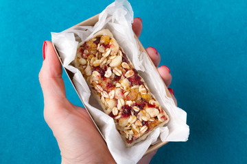 a female hand holds useful sweetness from nuts, oatmeal, honey, red berries, chocolate, raisins, dried apricots