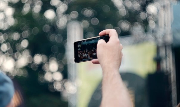 Mann fotografiert auf einem Konzert &uuml;ber eine Menschenmenge hinweg