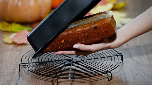 The woman removes pumpkin bread from baking form