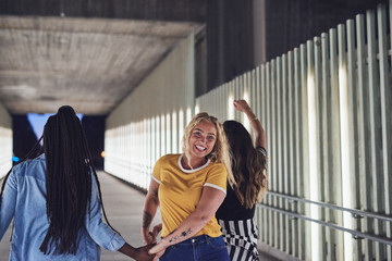 Laughing young girlfriends walking together in the city at night