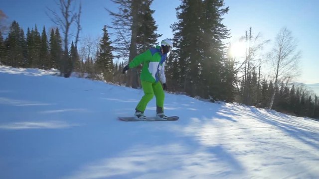 Sportsman snowboarder is drifting down on extreme snowboard upon a slope of the hill at sunny winter day