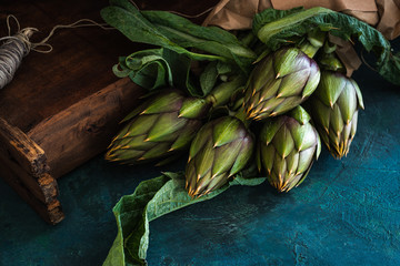 carciofi legati con spago appoggiati su legno  primo piano © faustalavagna