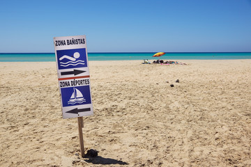 sign of bathing area on the beach for the safety of bathers compared to boats . " area sports" and "area bathers " write in Spanish language