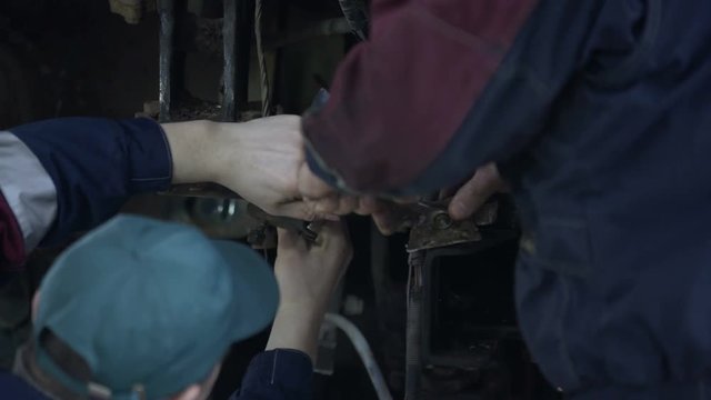 Two mechanic men repairing bus at workshop