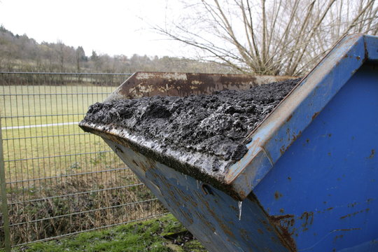 Abfallcontainer der mit kl&auml;rschlamm gef&uuml;llt ist. Der container ist &uuml;bervoll, der schlamm k&ouml;nnte bei der fahrt hinten heraus fallen.