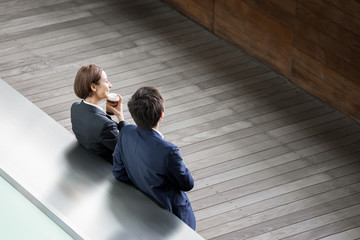 テイクアウトコーヒーを飲みながら話すカップル（ハイアングル）