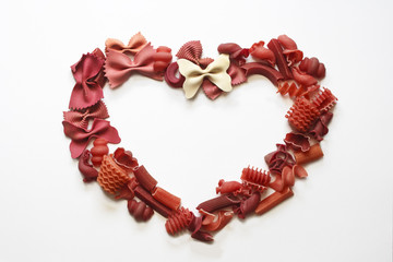 Obraz premium Mix of red pasta, laid out in the form of heart on white background