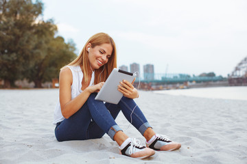 Young woman listening to music on the digital tablet