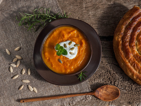 Pumpkin soup with cream and spanich pie on dark wooden background