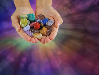Crystal healer offering selection of tumbled healing stones - female crystal therapist with cupped...