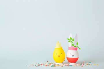 Easter holiday concept with cute handmade eggs: bunny and chicken on solid background
