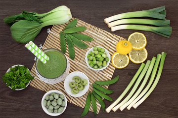 Fototapeta na wymiar Japanese macrobiotic diet food detox concept with fresh vegetables, fruit, wasabi paste and nuts and cold matcha tea with foods high in antioxidants, fibre, vitamins and minerals. On bamboo and oak.