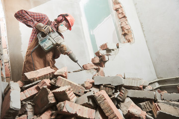 worker with demolition hammer breaking interior wall