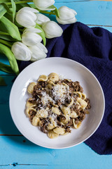 Ground beef and mushrooms pasta. Blue wooden table, white tulips.