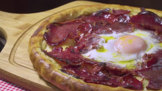 Turkish and Arabic Traditional Ramadan Food Pide or Pizza ingredients with Pastirma which is halal bacon, egg, mozzarella cheese, butter and spice on rustic white wood background. Rotating shot.
