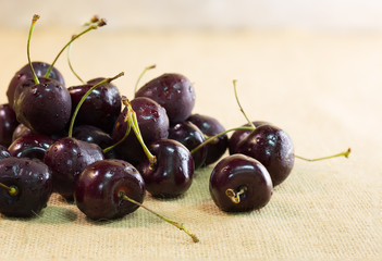 Pile of Fresh Cherrys in wooden bowl and fall out bowl on brown cloth background