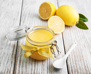 Lemon curd in glass jar with fresh lemons