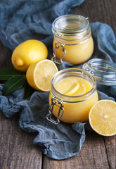 Lemon curd in glass jar with fresh lemons