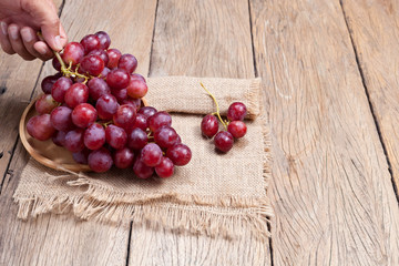 Red grapes on old wooden table background.