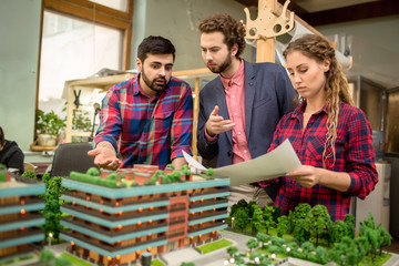 Group of three young professional architects working with layout of new city district