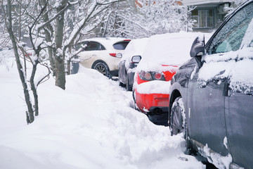 Cars under the snow in the city after heavy snowfall. Winter in the city concept. Toned.