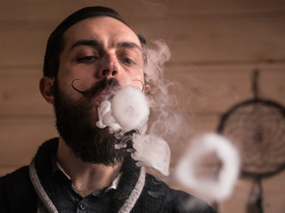 Man with Beard and Mustages Vaping an Electronic Cigarette. Vaper Hipster Smoke Vaporizer and...