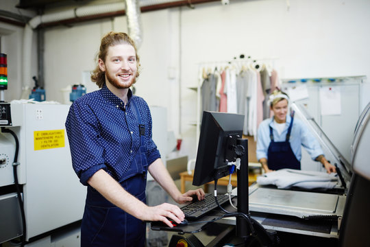 Happy man in uniform looking at camera while working in graphic typography office