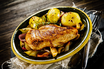Roast chicken breast with potatoes on wooden background