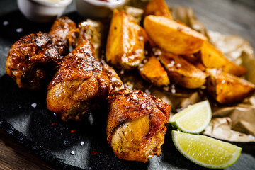 Grilled drumsticks with French fries wooden background