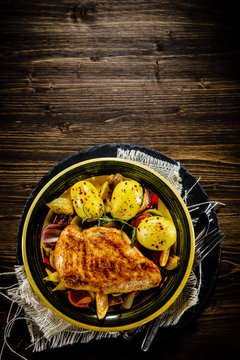 Roast chicken breast with potatoes on wooden background