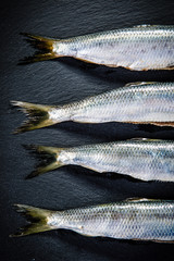 Fresh raw herrings on black stone