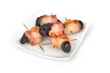 Leckere spanische Tapas: Getrocknete Pflaumen in Speck gerollt und gebraten, Freisteller – Delicious Spanish tapas on white background:  Fried prunes wrapped in bacon