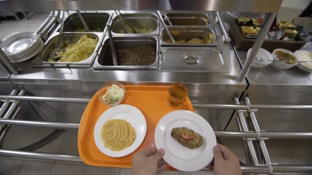 Point of view taking food on the tray in modern plant canteen